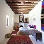 Dormitor simplu amenajat in stil marocan cu grinzi de lemn pe tavan